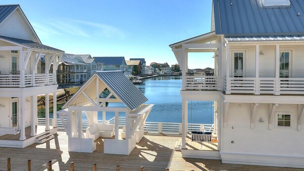 A waterfront property with multiple buildings, a wooden deck, and a view of the water.
