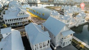 A coastal residential area with white houses, a marina, and a calm body of water.