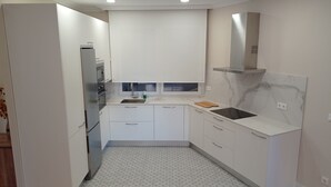 A compact kitchen with white cabinets, a built-in oven, a stainless steel sink, and a marble backsplash. - URDAIHOME APARTMENT (Gernika-Lumo)