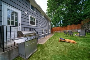 A backyard with a grill, chairs, and a wooden deck. - Waterview House Walking Distance from Cove Beach (Stamford)