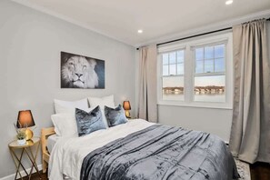 A bedroom with a bed, two bedside lamps, a window with curtains, and a wall-mounted picture. - Waterview House Walking Distance from Cove Beach (Stamford)