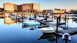 A marina with boats docked, wooden piers, and modern buildings in the background. - 5BR Beach House, Water Views, Game Room, Backyard (Stamford)