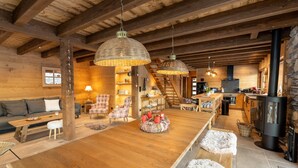 A cozy cabin interior with a wooden dining table, plush seating, and a stone fireplace. - Luxury chalet LE CARIBOU, near Gérardmer, exceptional view, jacuzzi. (Xonrupt-Longemer)