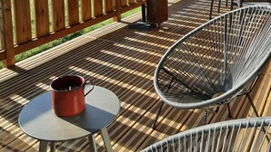 A wooden deck with a hammock, a table with a red mug, and a chair. - Luxury chalet LE CARIBOU, near Gérardmer, exceptional view, jacuzzi. (Xonrupt-Longemer)
