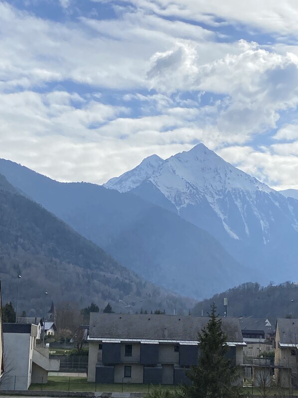 Ein Gebirge mit schneebedeckten Gipfeln unter einem teils bewölkten Himmel.