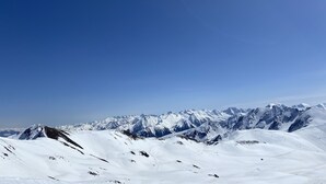 Eine verschneite Berglandschaft mit wolkenlosem, blauem Himmel.