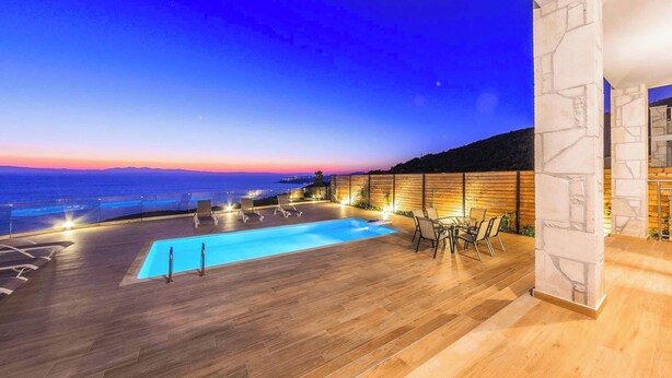 Zona de piscina al terrat amb vista al mar al capvespre.