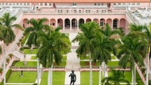 A large, pink building with a central courtyard, surrounded by palm trees and featuring a statue in the middle. - Serene Resort-style Villa minutes to Siesta Key, in popular Village des Pins (Sarasota)