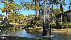 A tranquil pond with a fountain, surrounded by lush greenery and tall trees. - Serene Resort-style Villa minutes to Siesta Key, in popular Village des Pins (Sarasota)