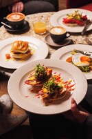 A dining table with plates of food, a cup of coffee, and a glass of orange juice.