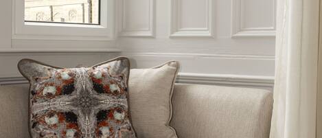 A corner sofa with a decorative pillow and a view of a building through a window.