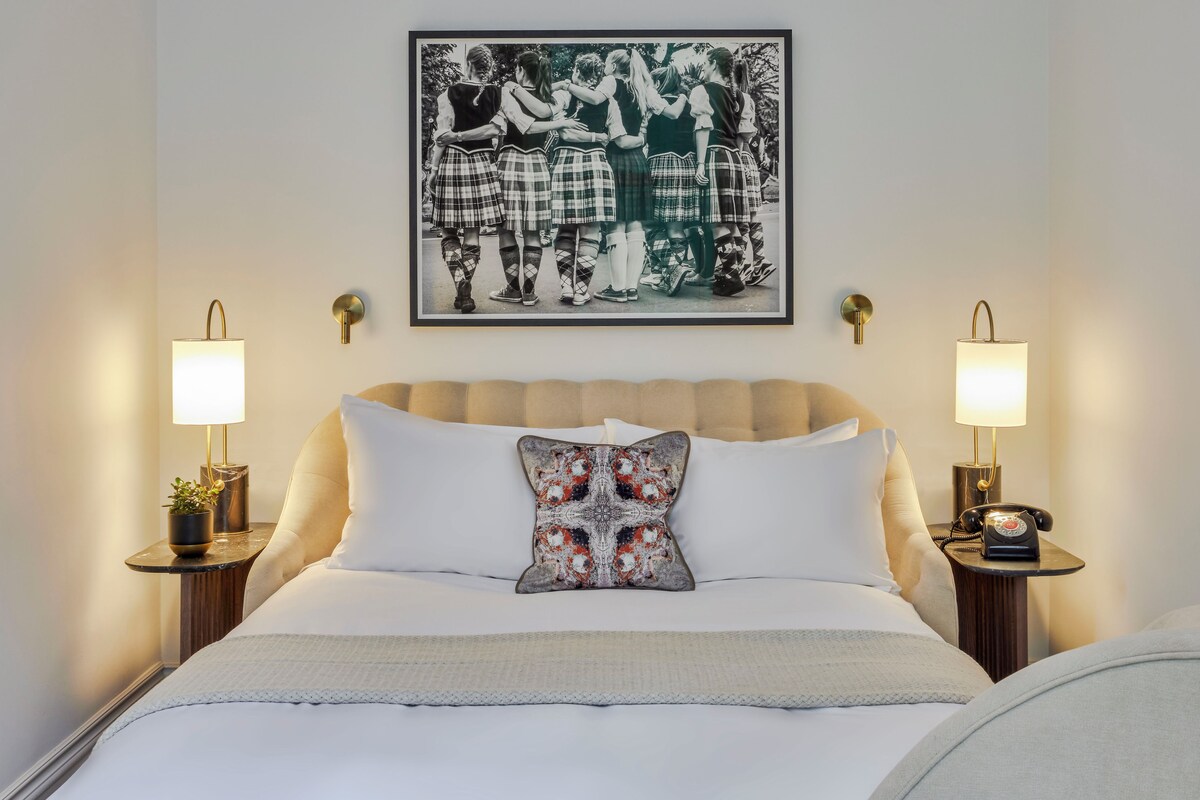 A neatly made bed with a decorative pillow, two bedside lamps, and a framed picture above the bed.
