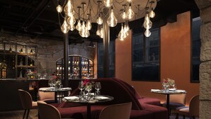 A restaurant with round tables, red upholstered seating, and hanging light fixtures.