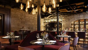 A restaurant interior with stone walls, hanging light fixtures, and bar area with shelves of bottles.