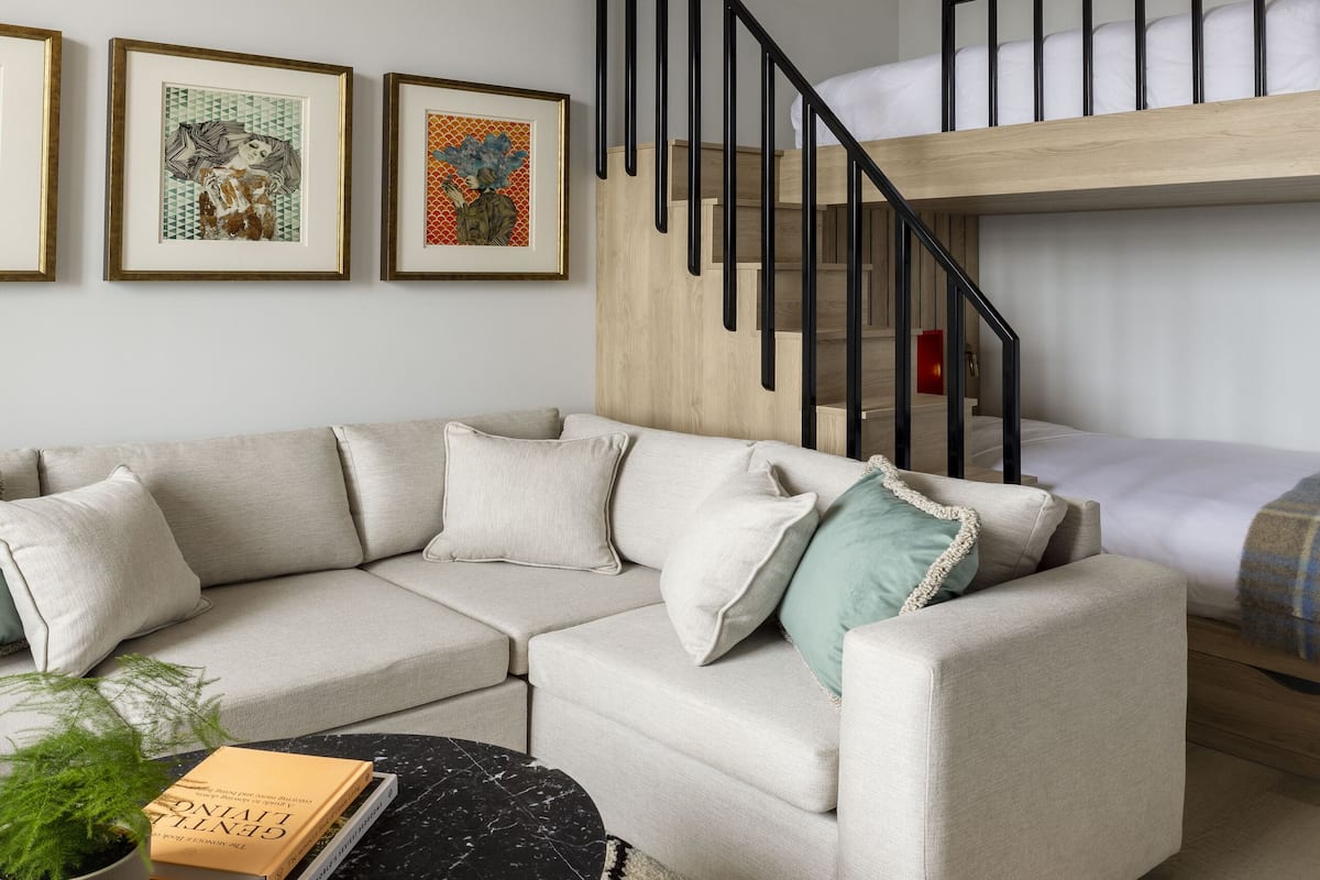 A modern living room with a sectional sofa, a black marble coffee table, a staircase with a wooden finish, and framed artwork on the wall.