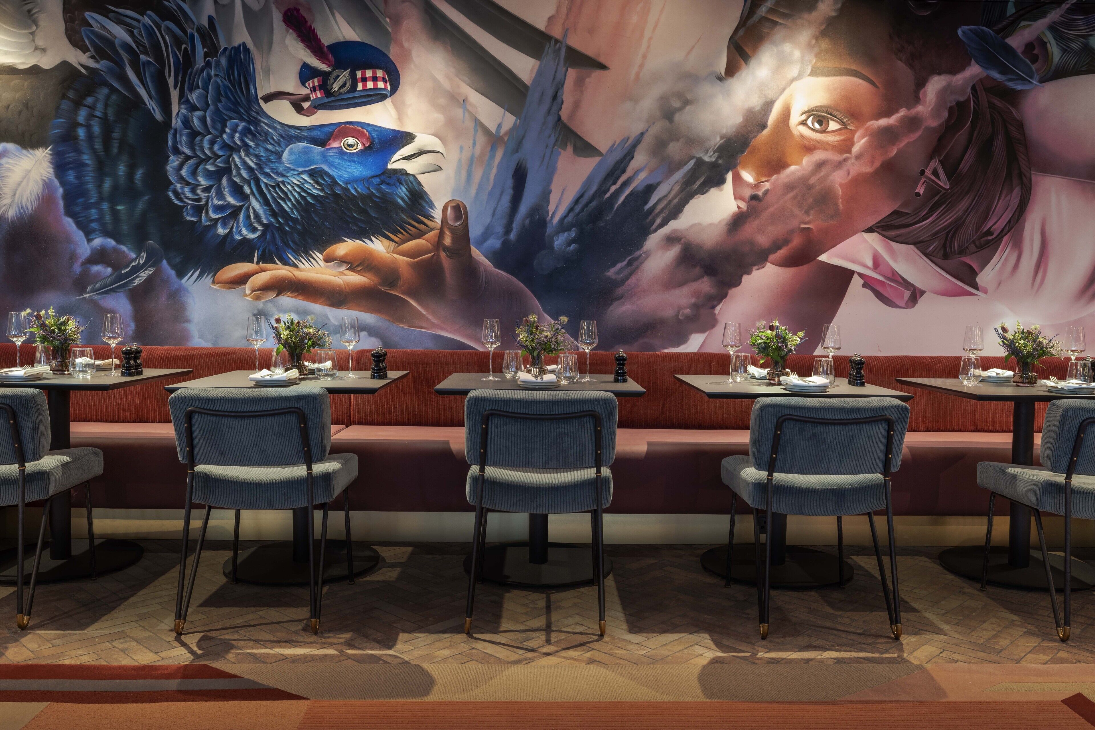 A restaurant with booths and tables, each set with wine glasses and flowers.
