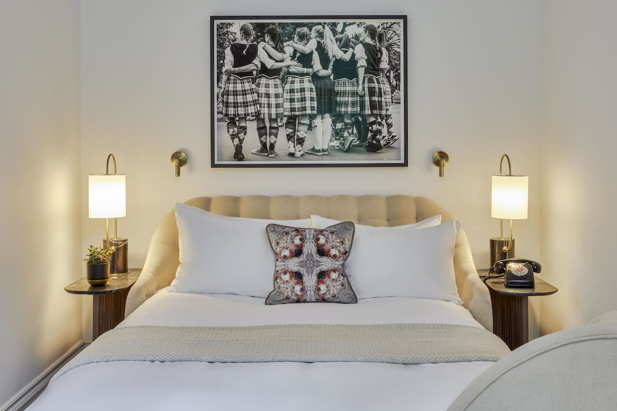A neatly made bed with a decorative pillow, two bedside lamps, and a framed picture above the bed.