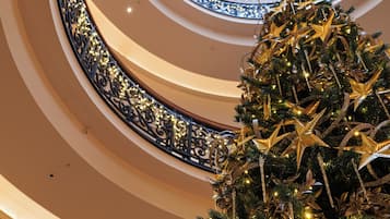 A multi-level atrium with a central glass dome ceiling and a decorated Christmas tree.