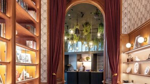A hallway with a patterned rug, wooden bookshelves, a reception desk, and a blue carpeted area.