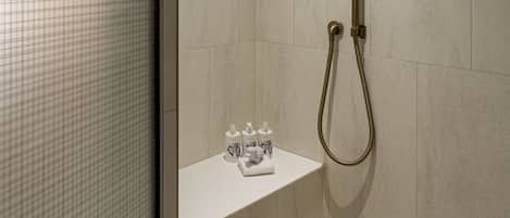 Une douche moderne dotée d’un pommeau de douche à main et d’un flexible également à main.