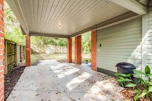 A covered patio area with a concrete floor, brick pillars, and a white ceiling.