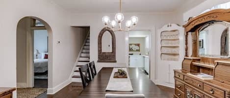Comedor con una mesa larga, sillas, candelabro y un aparador de madera con espejo.