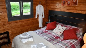 Ein Zimmer mit Holzboden, einem Bett, einem Fenster und einem Gemälde.