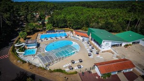 Vista aérea de un resort con una gran piscina, varias áreas de descanso y un edificio con techo verde.