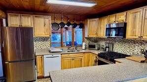 A kitchen with wooden cabinets, a stainless steel refrigerator, a microwave, a toaster, and a dishwasher. - Spacious Adirondack House in Otter Lake (Forestport)