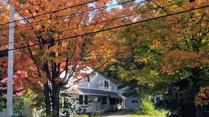 A house with a porch and a driveway, surrounded by trees with autumn foliage. - Spacious Adirondack House in Otter Lake (Forestport)