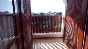 Un balcón con vista a un paisaje urbano, puertas de madera y suelo de baldosas.