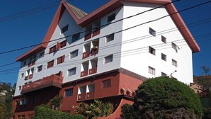 Un edificio de varios pisos con balcones, una decoración en rojo y blanco, y líneas eléctricas visibles.
