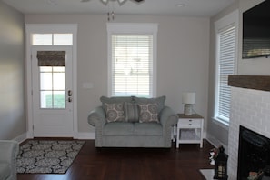 A living room with a sofa, a fireplace, a patterned rug, and a door with a window.