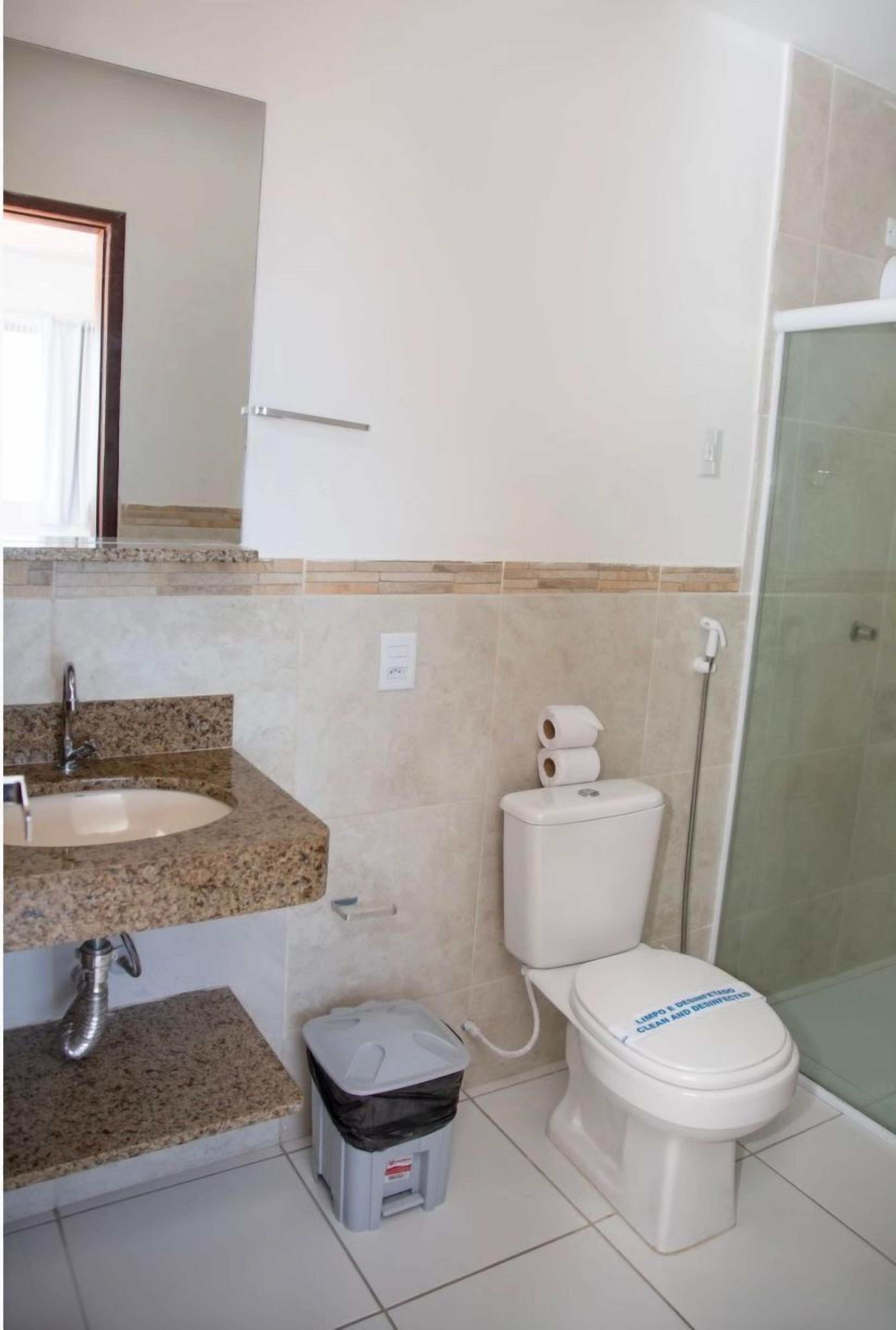 Baño con lavamanos de encimera de granito, inodoro y cabina de ducha de vidrio.
