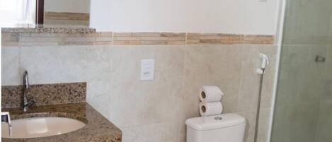 Baño con lavamanos de encimera de granito, inodoro y cabina de ducha de vidrio.