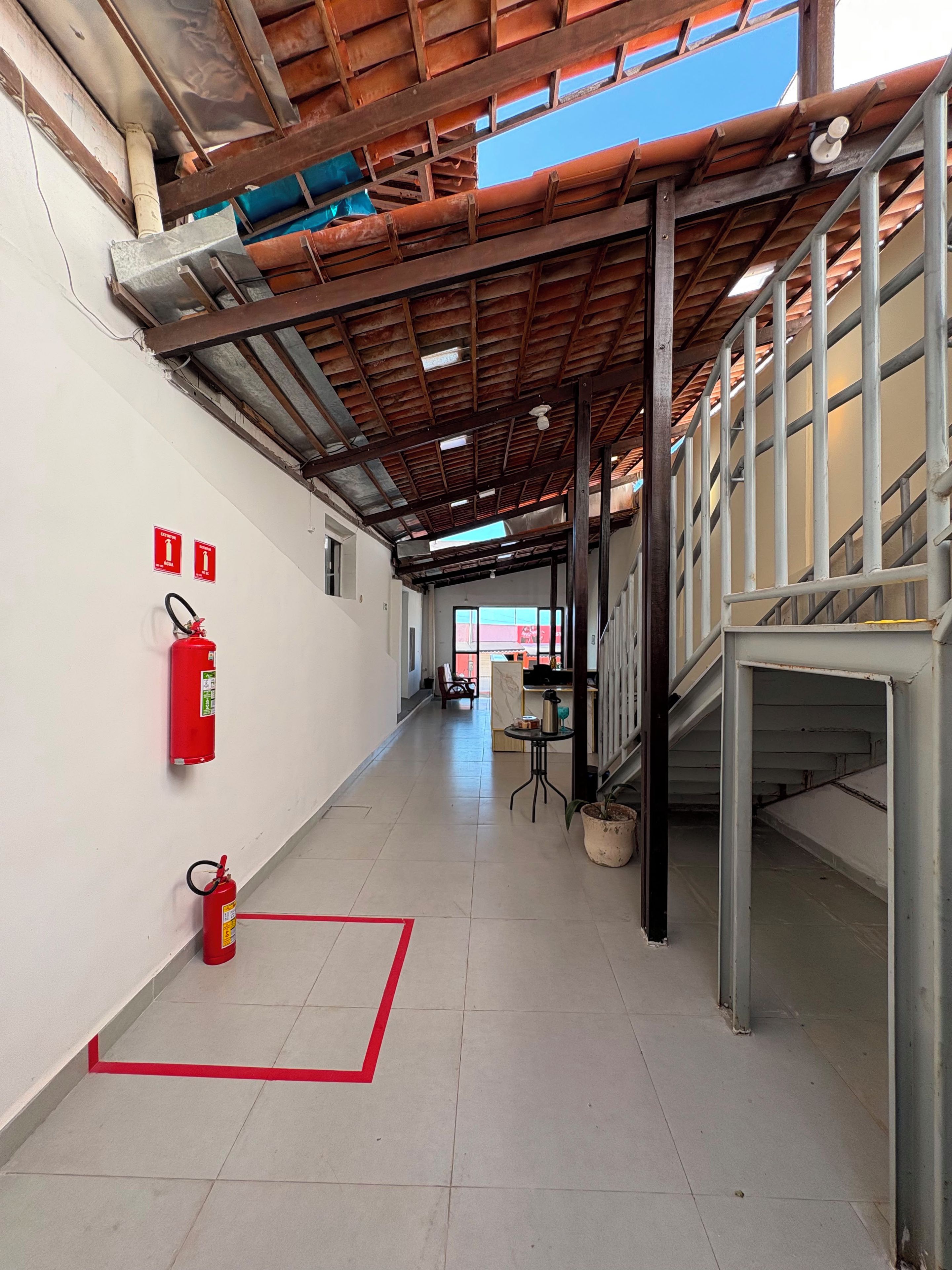A corridor with a tiled floor, fire extinguishers, and a red safety line.