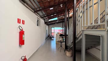 A corridor with a tiled floor, fire extinguishers, and a red safety line.