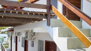 A staircase with wooden railings leading to a building with multiple doors, each marked with a number. - Hotel Pousada Encanto da Praia  (Natal)
