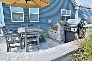 Un patio con mesa y sillas, una parrilla y una jardinera de piedra.