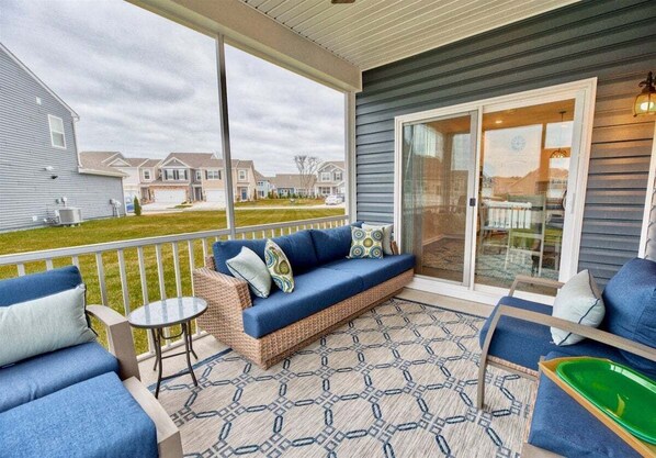 A covered patio with a sofa, chairs, and a small table.