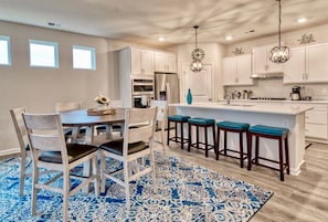 Uma cozinha moderna com armários brancos, uma ilha central com banquetas e um tapete estampado.