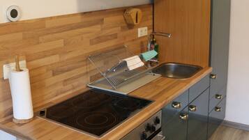 Een kleine keuken met een houten aanrecht, roestvrijstalen apparatuur en een ingebouwde magnetron.