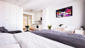 Ein modernes Hotelzimmer mit einem großen Bett, einem Schreibtisch, einem Sessel und einem Fernseher, der eine Reise-App anzeigt.