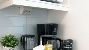 Eine Küche mit Mikrowelle, Kaffeemaschine und verschiedenen Küchenutensilien auf der Arbeitsfläche.
