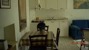 A compact living space with a dining area, kitchenette, and a sofa. - Two-room apartment in the countryside a stone's throw from the sea (Calice Ligure)