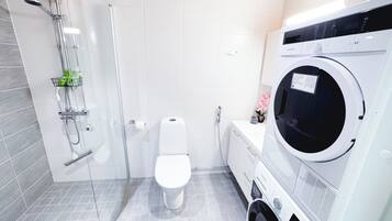 Een moderne badkamer met een douche, toilet en een voorlader wasmachine.
