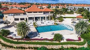 A resort with a central swimming pool, lounge areas, and a view of surrounding buildings. - A Gem at Gold Coast: 2 BDR Townhouse-Pools and Gym (Oranjestad)