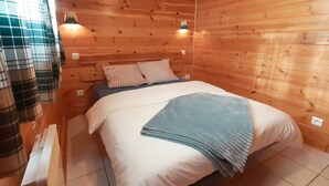 Ein Zimmer mit Holzwänden, einem Bett, Kissen und einer Decke.