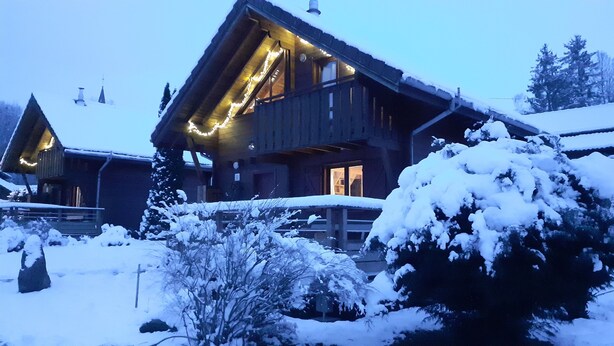 Eine Holzhütte mit Balkon und verschneiter Landschaft.