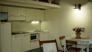 Una cucina compatta con mobili bianchi, un forno a microonde, un lavello e un tavolo da pranzo con sedie.